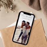 Digitales Save-the-Date für eine Hochzeit auf einem Smartphone-Display. Die Einladung zeigt ein Paar am Strand, personalisiert mit Namen und Datum. Das Smartphone liegt auf einem Umschlag im warmen Flatlay-Stil. Moderne digitale Hochzeitseinladung zum Selbstbearbeiten und Versenden per Smartphone.